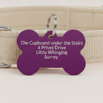 Purple bone-shaped dog tag engraved with a full address showing how much text can be fitted clearly